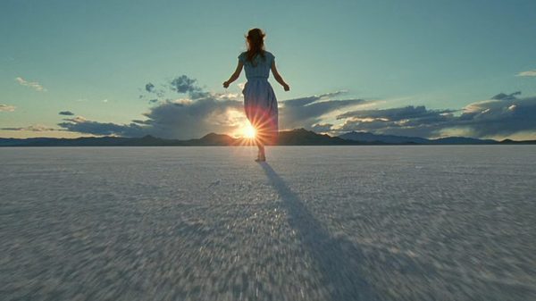 The Tree of Life film image; woman walking across sand towards a sunset