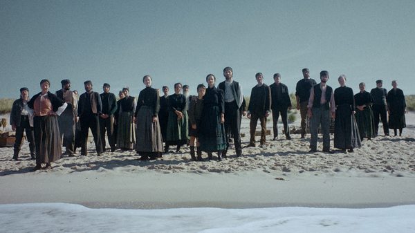 Trial of Hein film image; large crowd of people standing on a beach looking out to the water