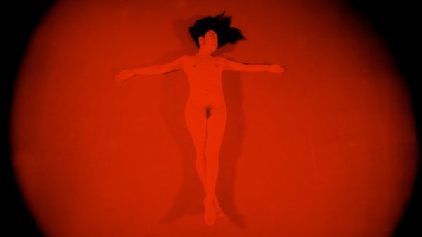 Tristesse film image; woman lying under a red spotlight
