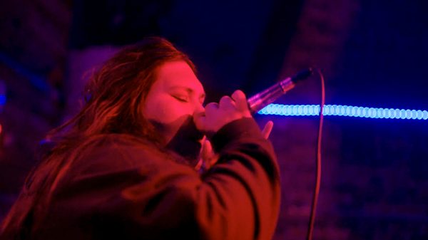 Turtle Island Rap film image; woman singing into a microphone