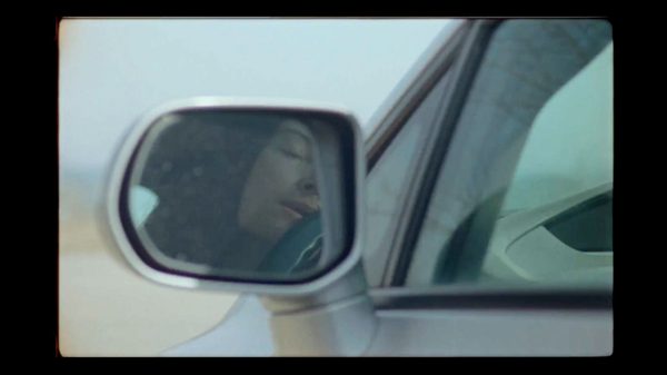 Two Hander film image; reflection of someone in a car side mirror