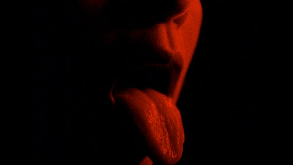 Vulnus film image; person sticking their tongue out under red lighting