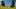 Wild Horse Nine film image; two people sitting in long grass by two large stone head statues