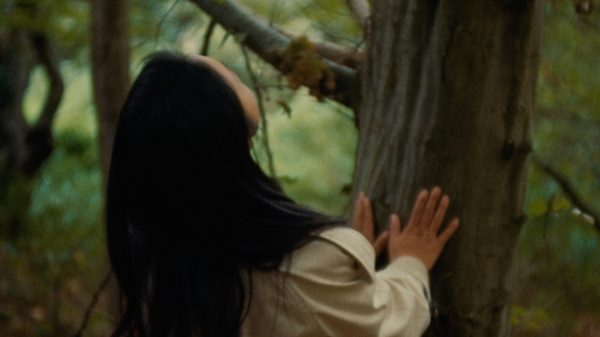 The Wind, One Brilliant Day film image; woman touching a tree trunk