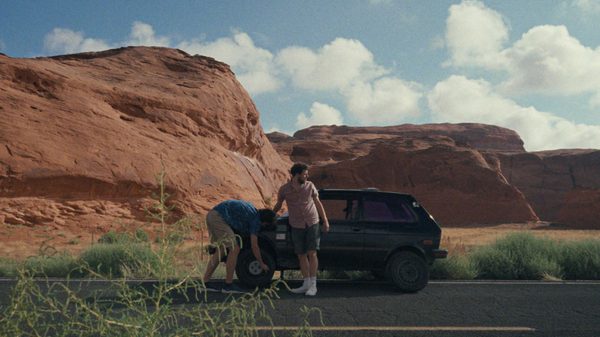 Yugo Goes to America film image; two men trying to fix a car on the side of a road