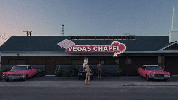 Yugo Goes to America film image; a person standing outside a Las Vegas chapel
