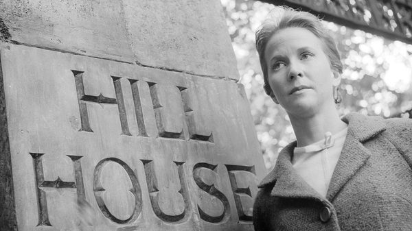 The Haunting film image; woman standing next to a stone pillar