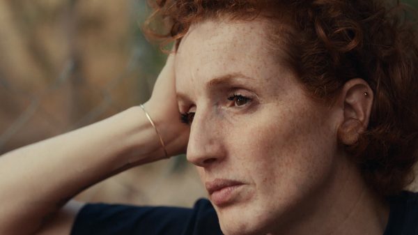 House of Hope film image; woman resting her head on her hand