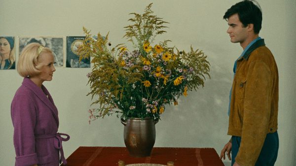 Le Bonheur film image; two people standing by a table with a giant vase of flowers