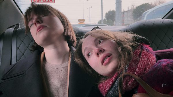 My Undesirable Friends: Part II film image; two people leaning against the back seat of a car