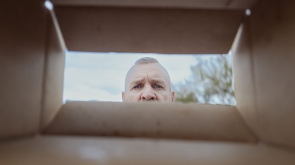 The Sandbox film image; perspective from inside an open box with a face peering into it