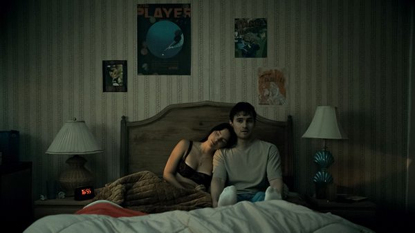 woman leaning on a guy's shoulder while they sit in bed
