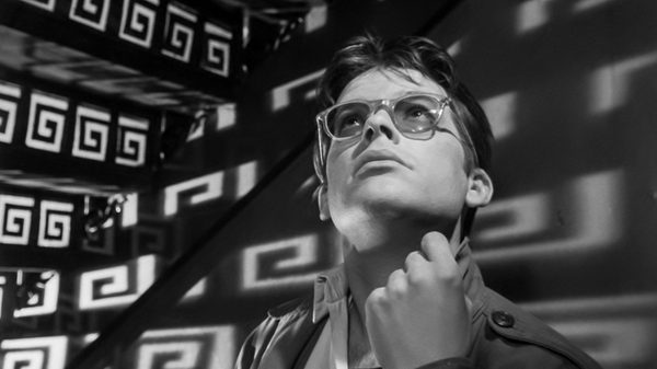 Ashes and Diamonds film image; man in a room with symbols reflected on the walls
