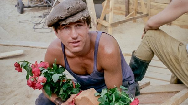 Man of Marble film image; man crouching holding a bouquet of flowers